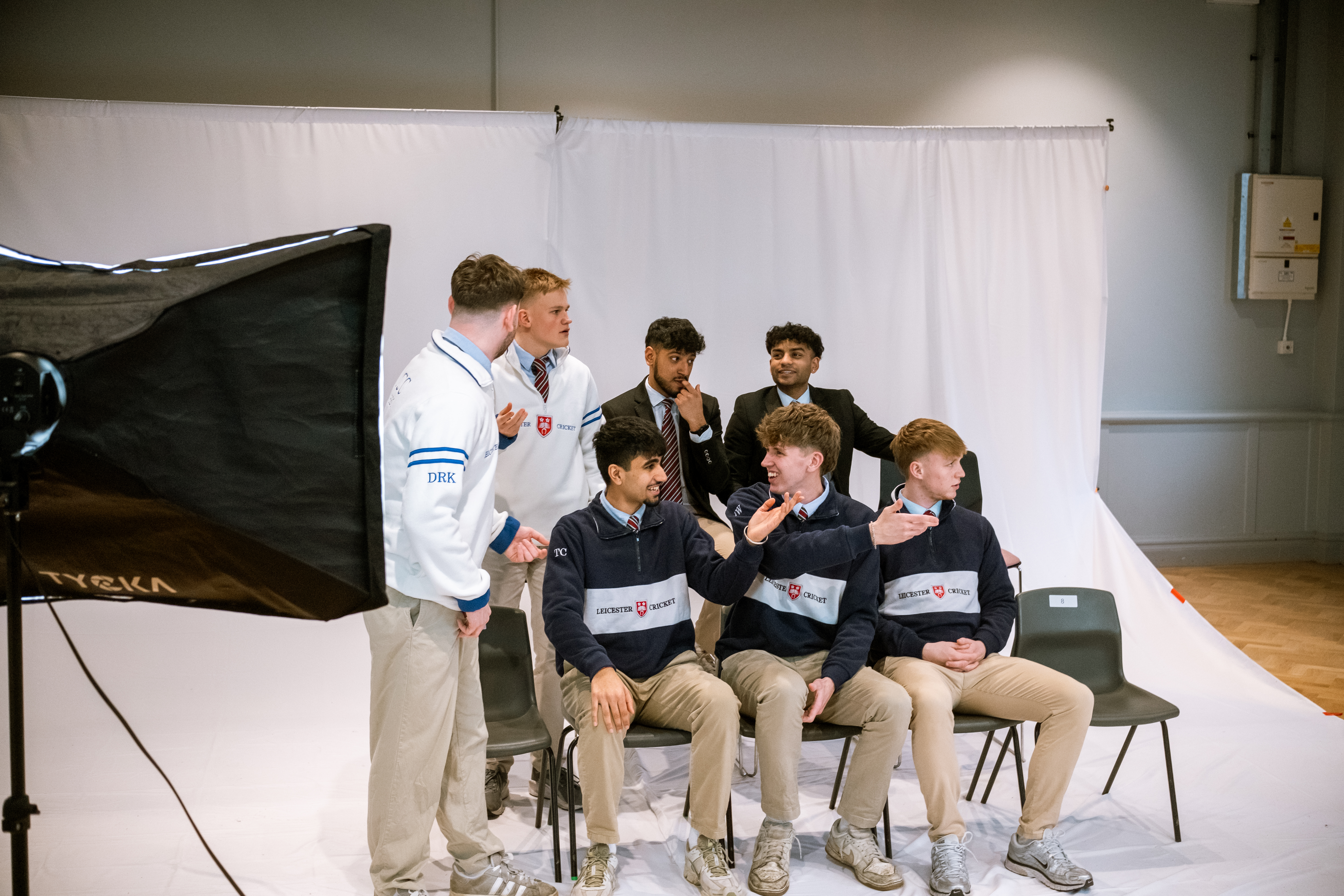 Illustration of 2 people, one sat using a laptop and one standing holding a phone and book