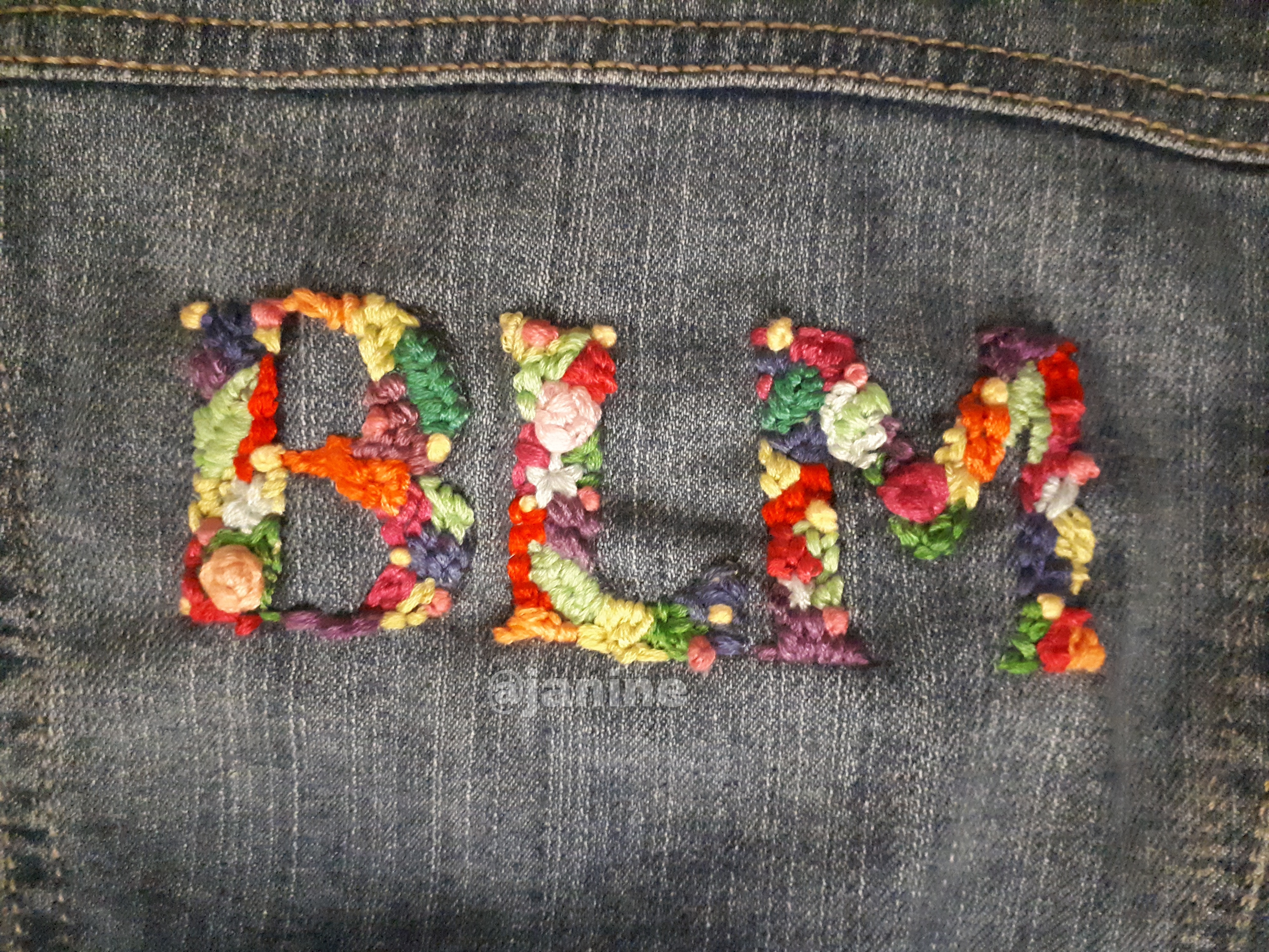 'BLM' embroidered onto jean material using lots of colours and flowers.
